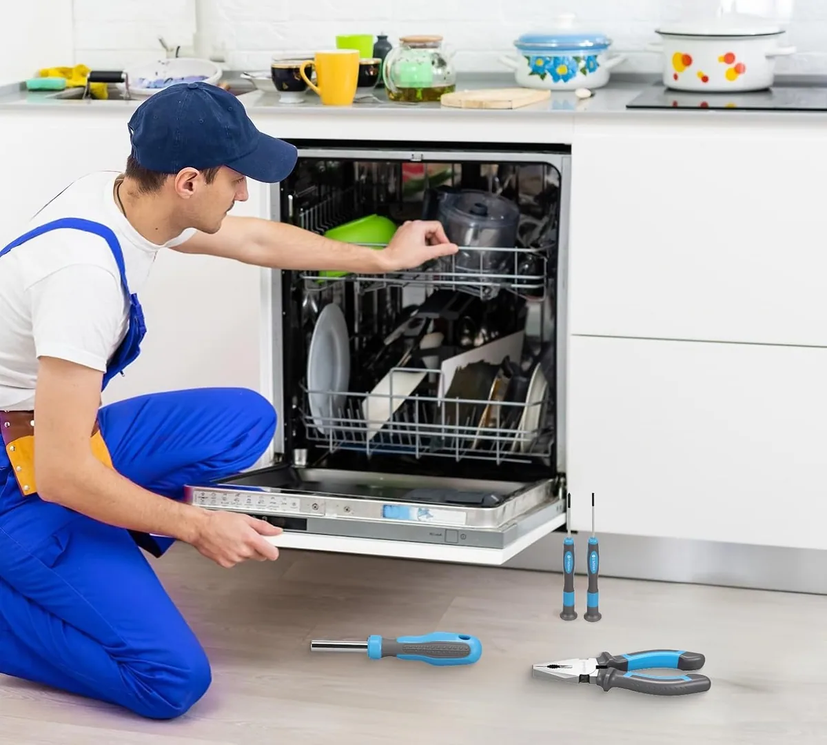 A repairman kneeling at a dishwasher with DOMINOX screwdrivers and pliers on the floor